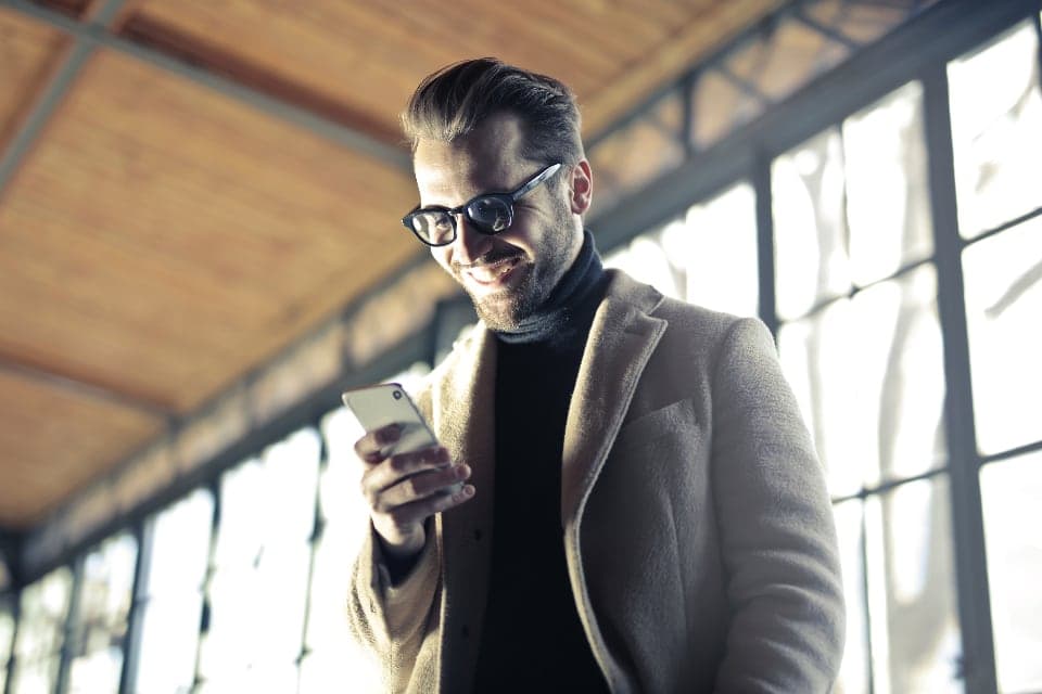 A man smiling at a message on his phone