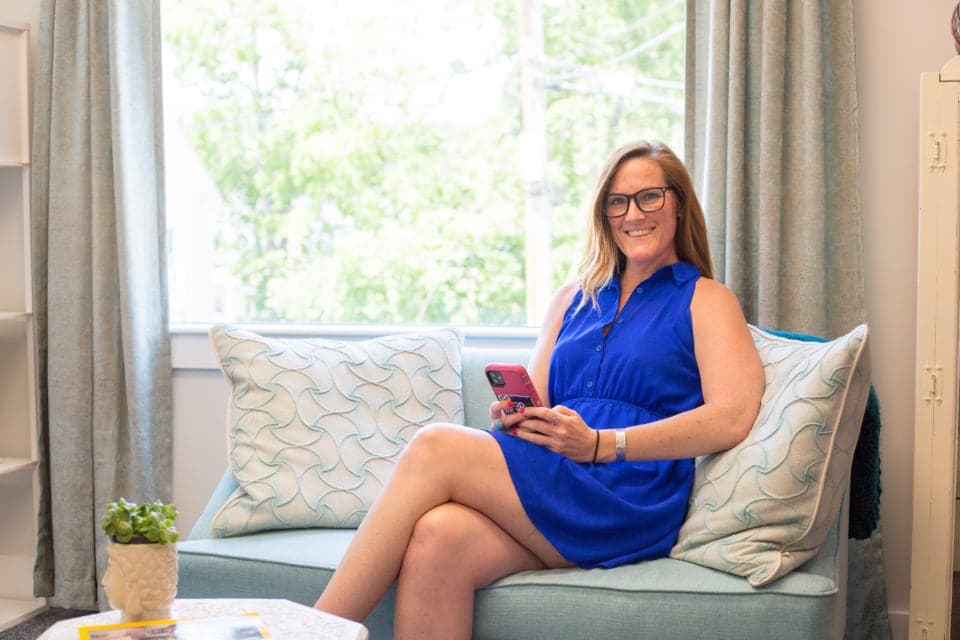 A woman at home on a sofa, messaging on her phone